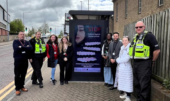 A poster displayed at a bus shelter pictured with students and Ashfield District Council reps