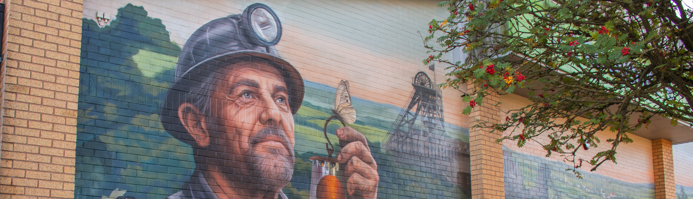 A group of people stood in front of a wall featuring a mural of a miner holding a lamp