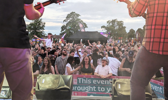 a crowd of people singing along in front of a stage 