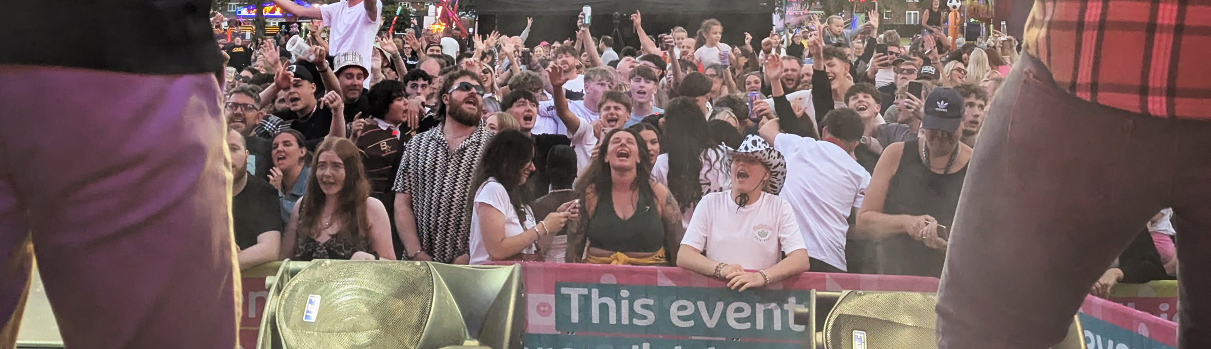 a crowd of people singing along in front of a stage 