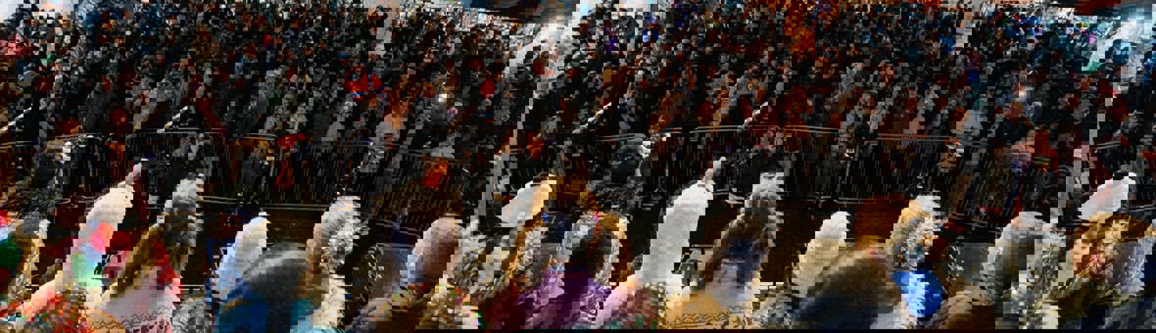 Children on stage look over a crowd of people in Sutton with a market behind them