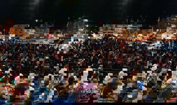 Children on stage look over a crowd of people in Sutton with a market behind them