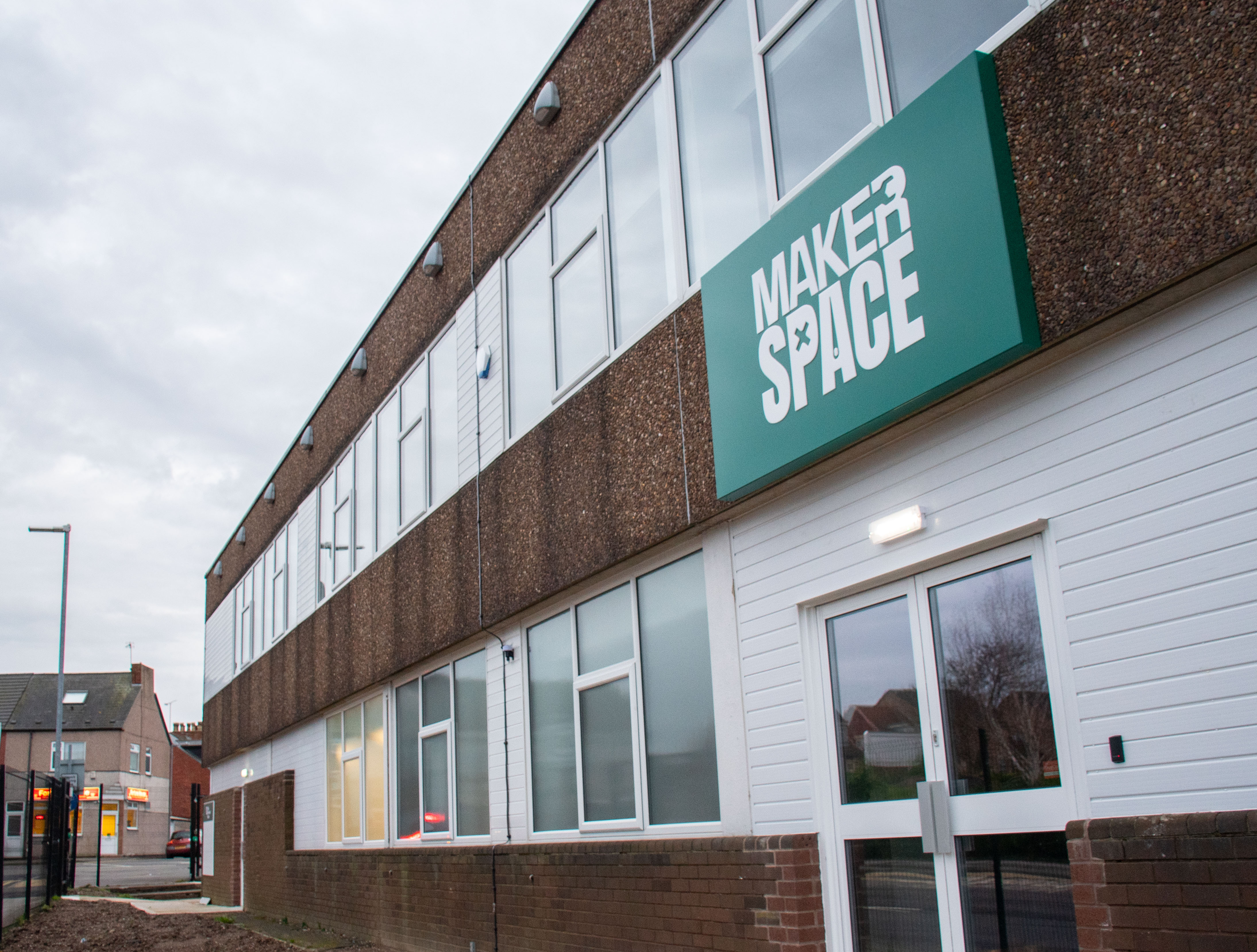 A green sign that reads MakerSpace on a pebbledash building 
