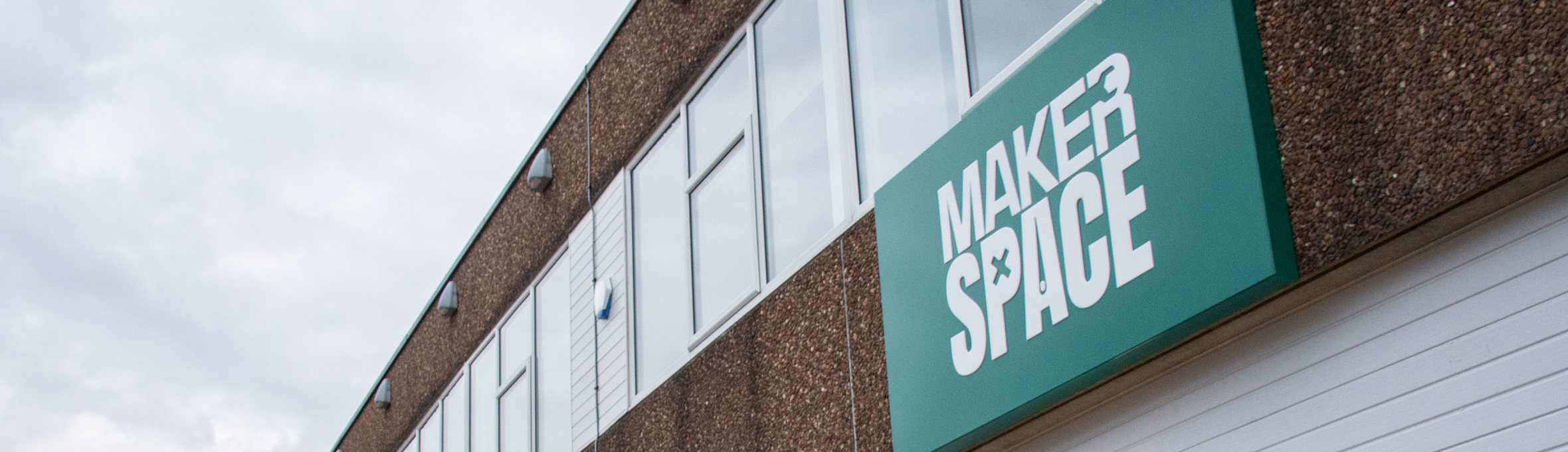 A green sign that reads MakerSpace on a pebbledash building 