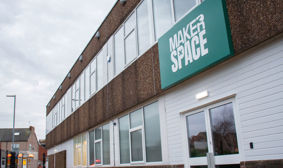 A green sign that reads MakerSpace on a pebbledash building 