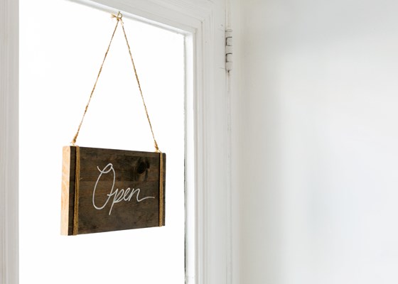 Wooden sign reading Open on white glass door