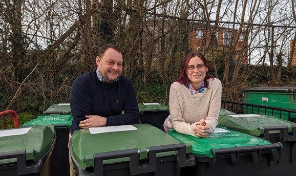 Councillor Jason Zadrozny and Helen-Ann Smith lean on green lidded bins 