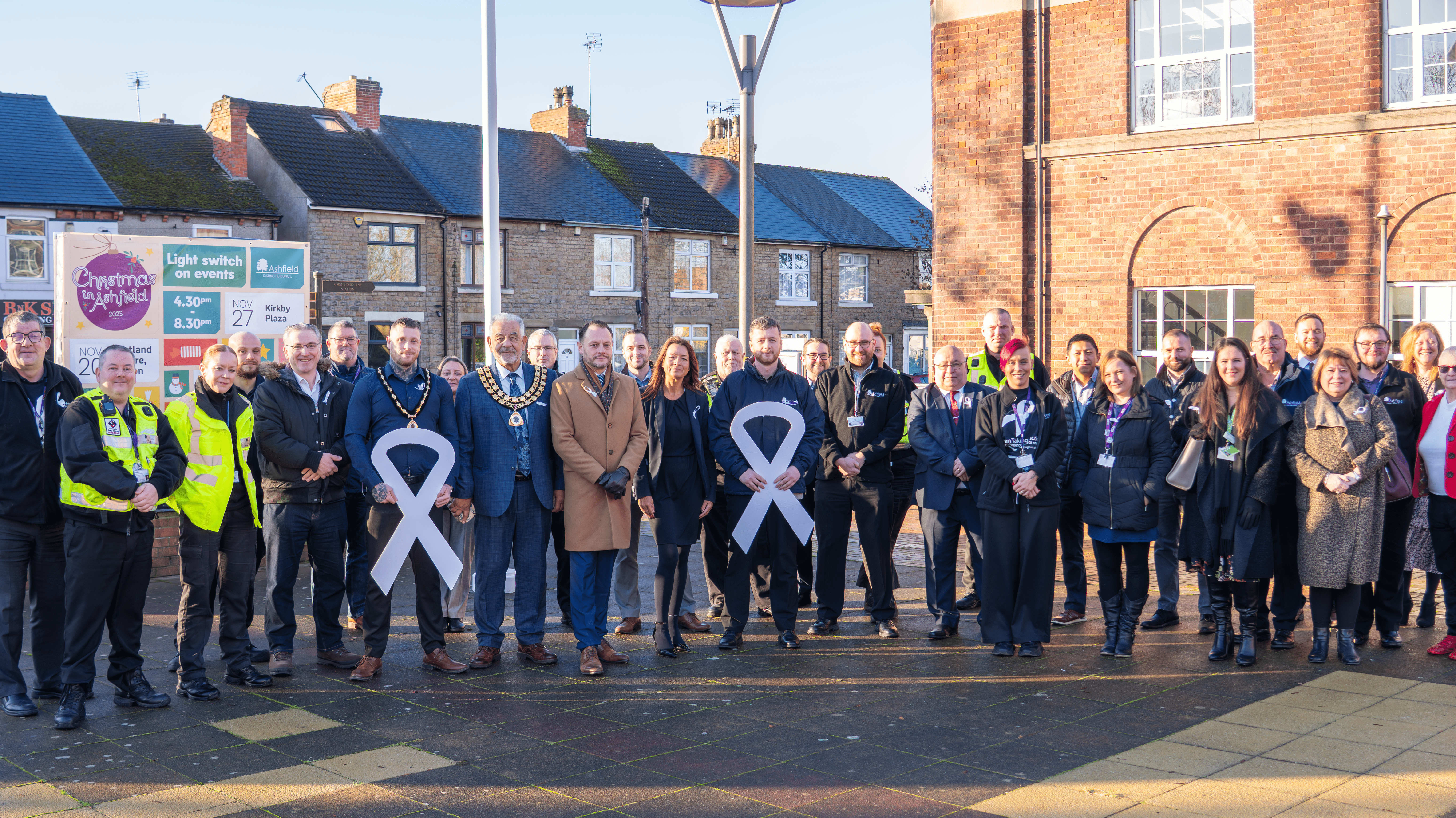 Council officers and Members all wearing white ribbons smile at the camera 