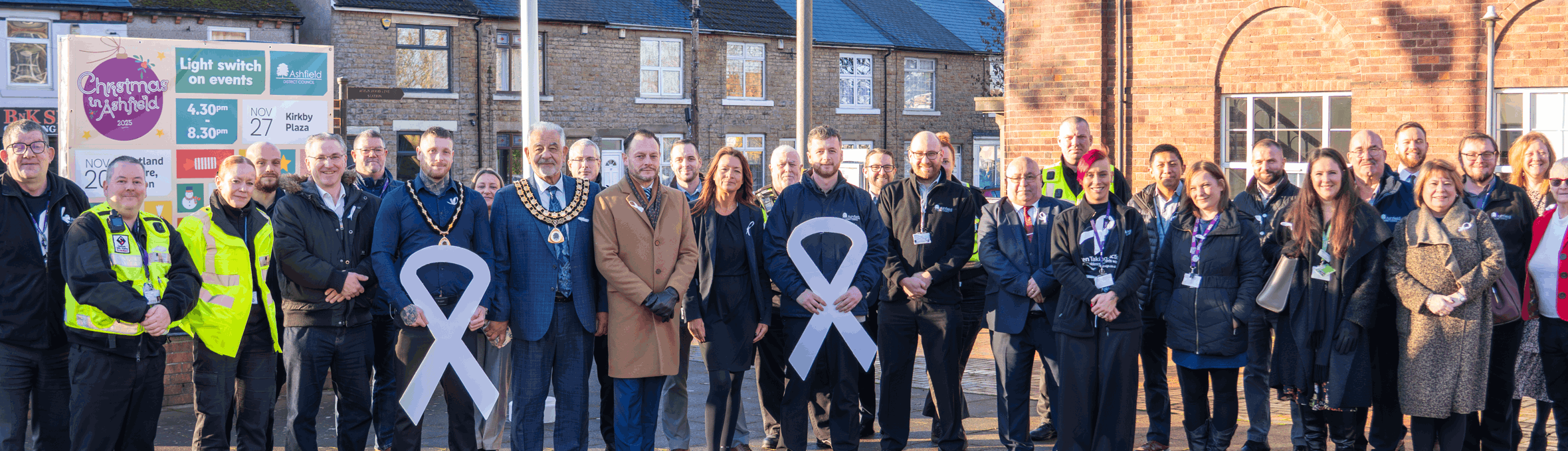 Council officers and Members all wearing white ribbons smile at the camera 