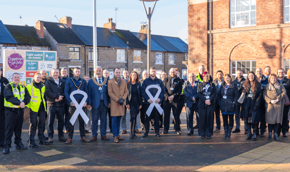 Council officers and Members all wearing white ribbons smile at the camera 