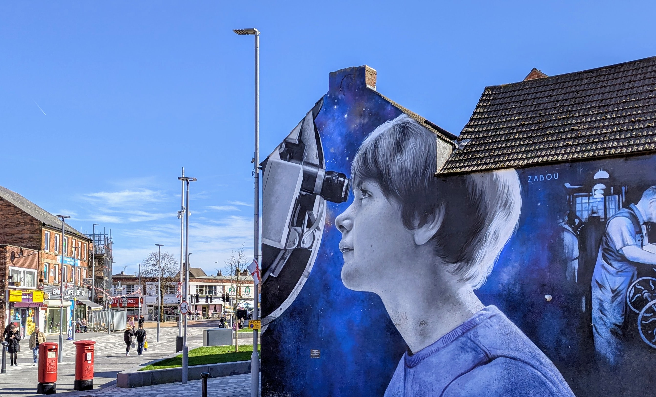 A photo-realistic mural on the side of a building shows a young girl looking through a telescope