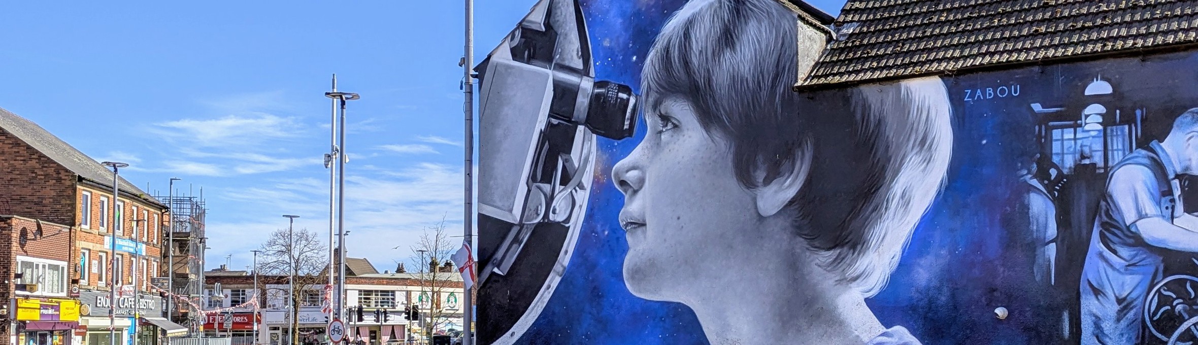 A photo-realistic mural on the side of a building shows a young girl looking through a telescope