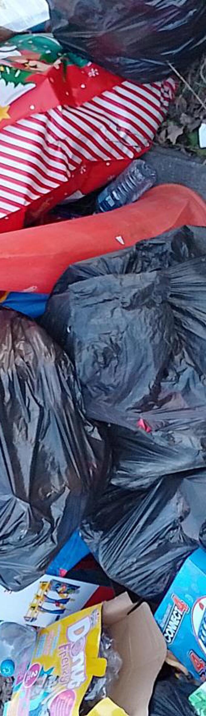 Several black bin bags and a smyths toy bag are dumped with rubbish overflowing