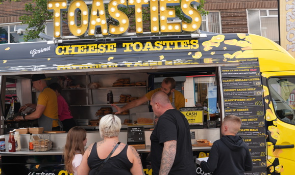 a family in front of a yellow van that says toasties 