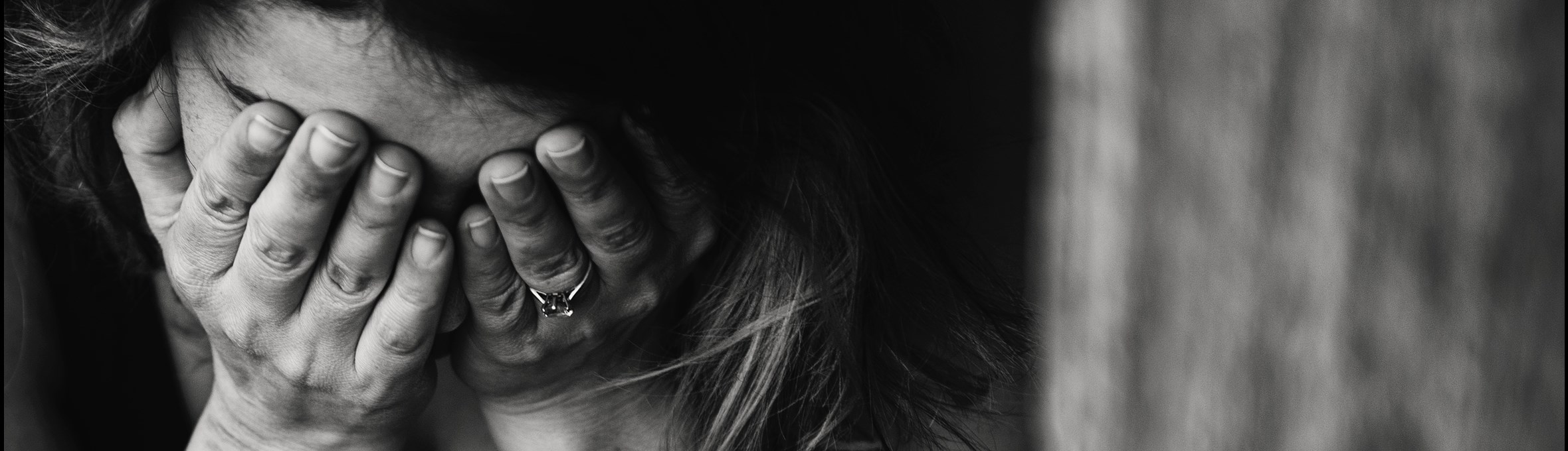 A woman pictured with her head in her hands in black and white