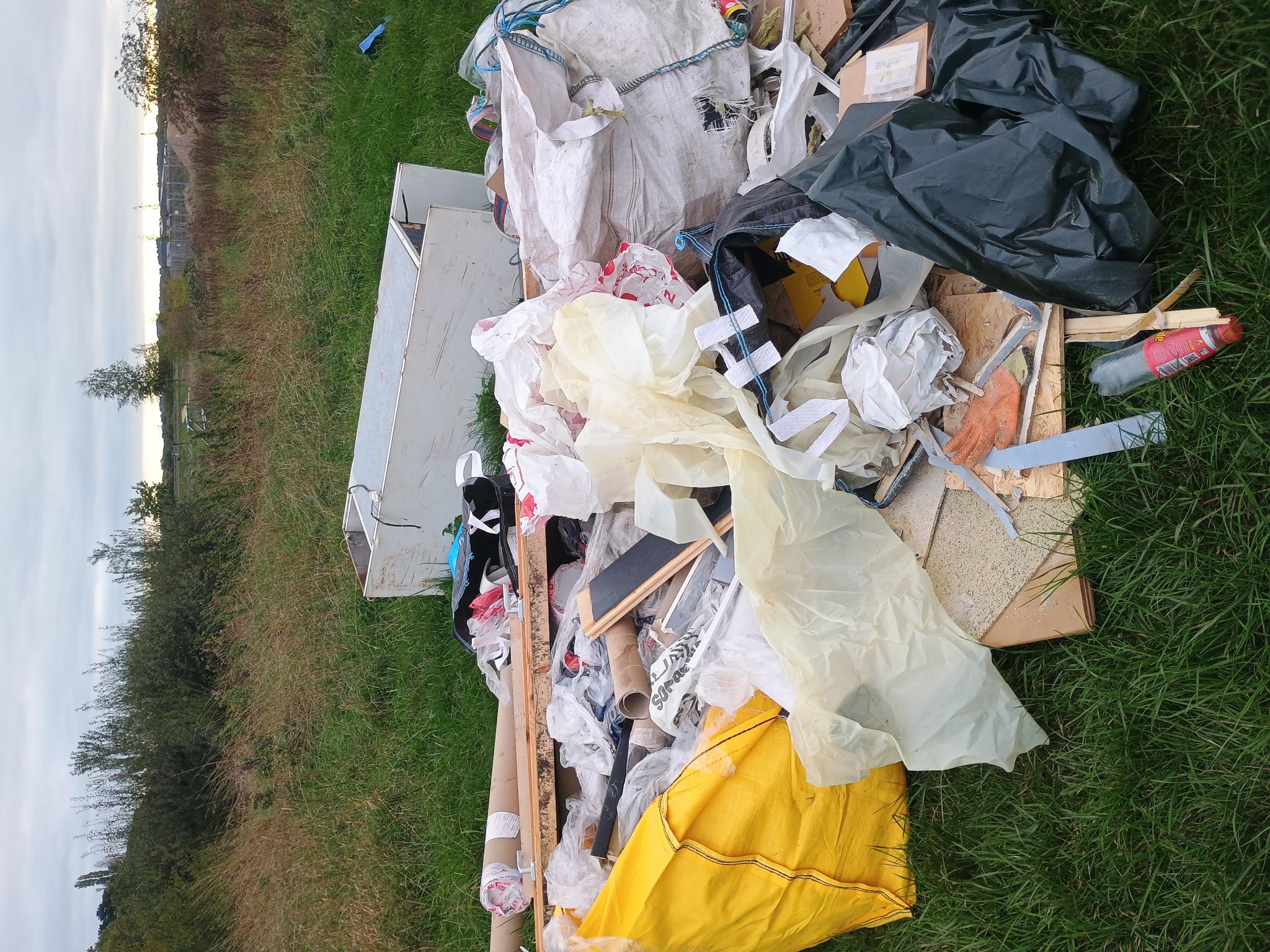 A large fly tip with black bags, builders bags and cupboards 