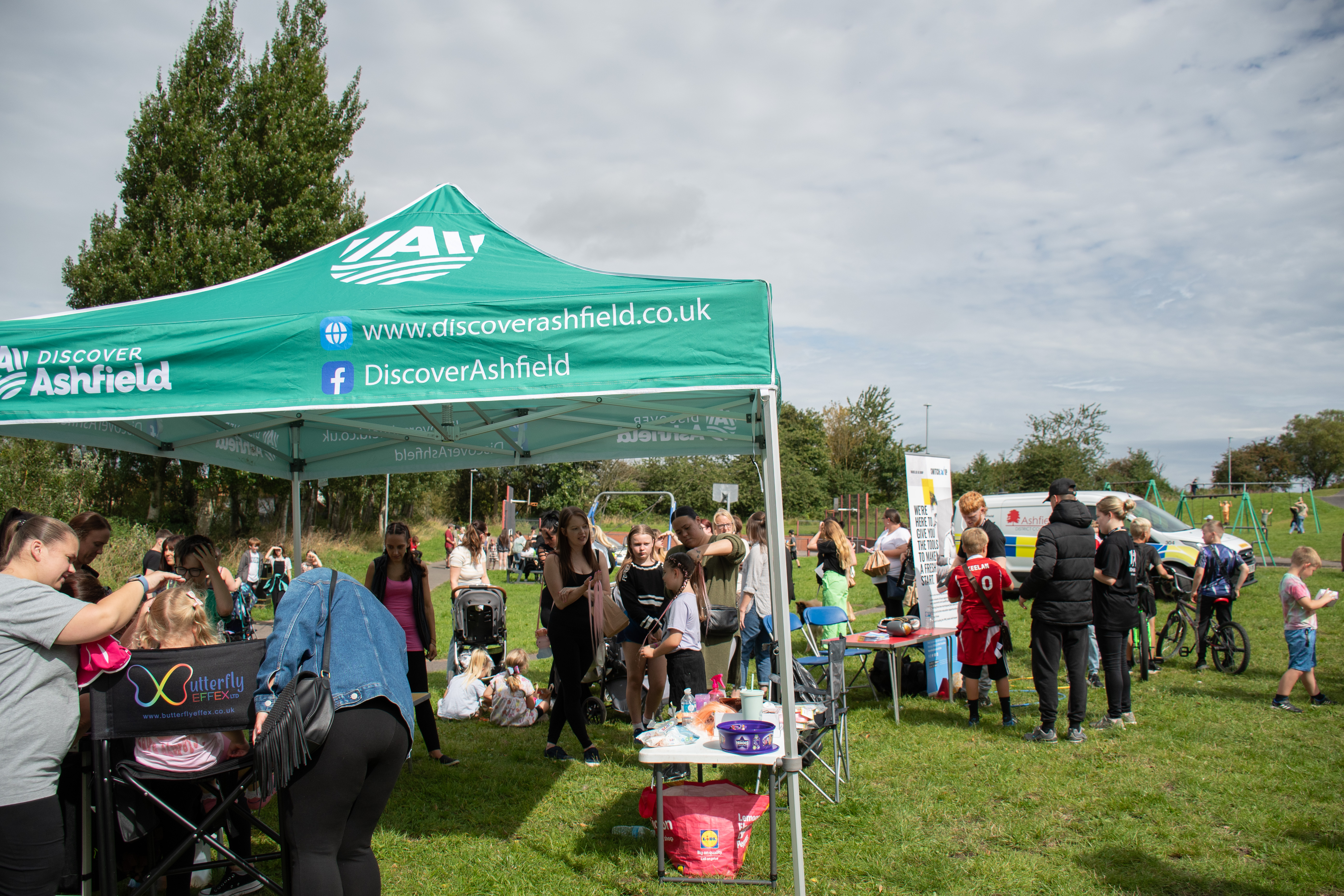 crowds of people queuing for face painting and hair braiding 