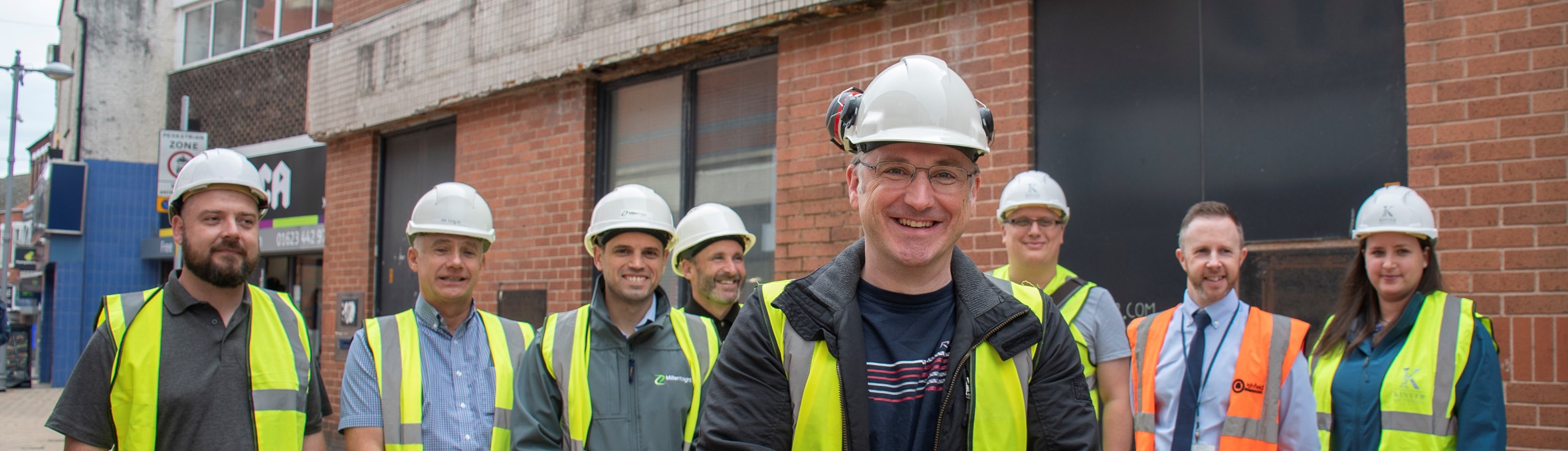 Cllr Matthew Relf stands in a high vis jacket and hard hat with several other people behind him 