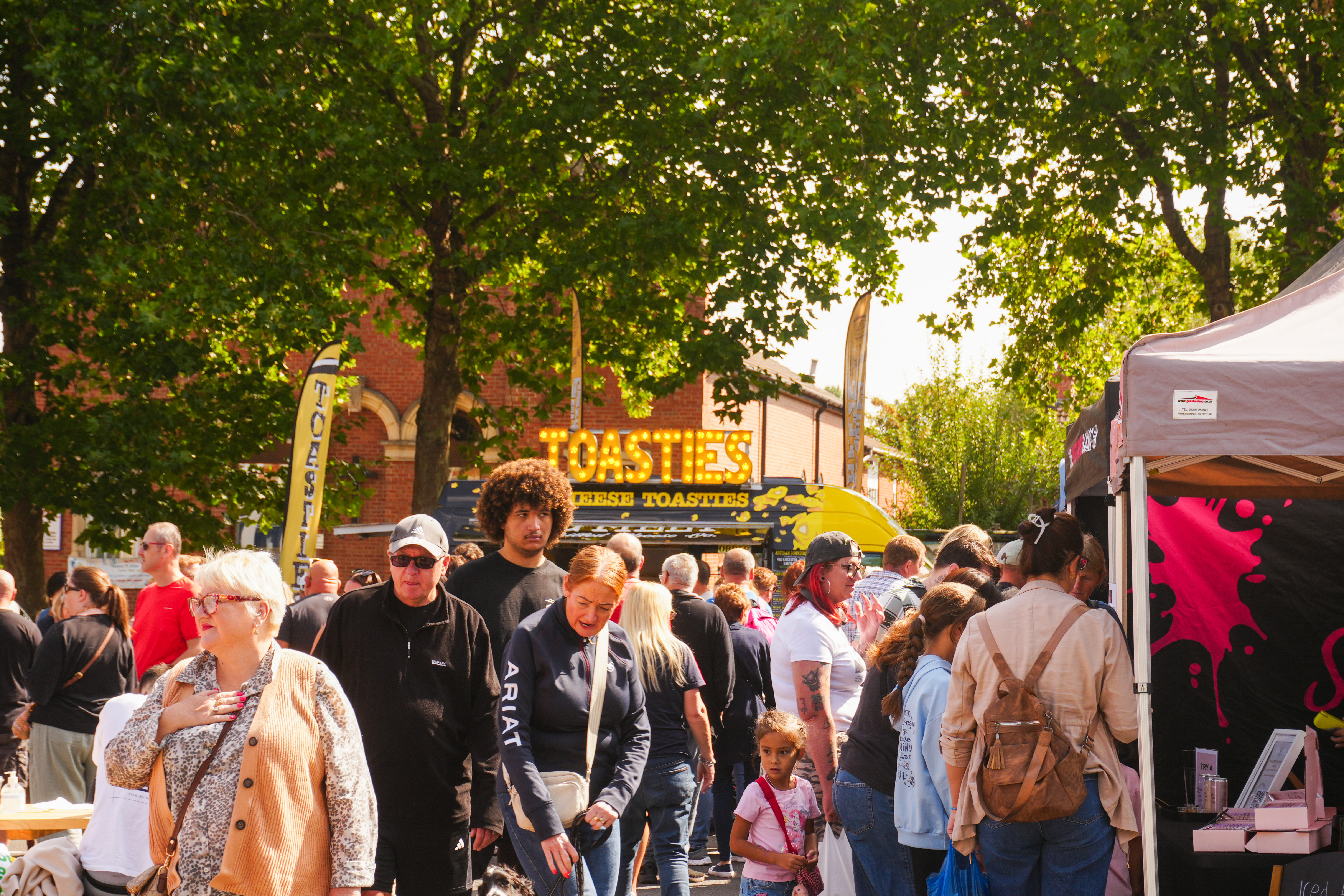 a crowd of people stood in front of various food stalls 