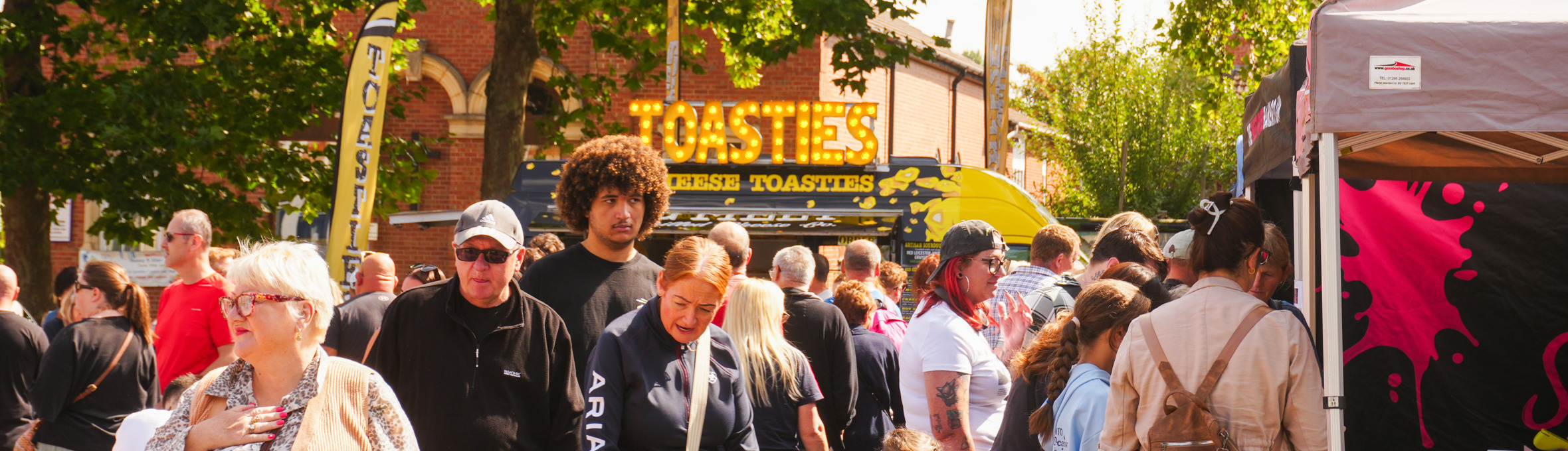 a crowd of people stood in front of various food stalls 