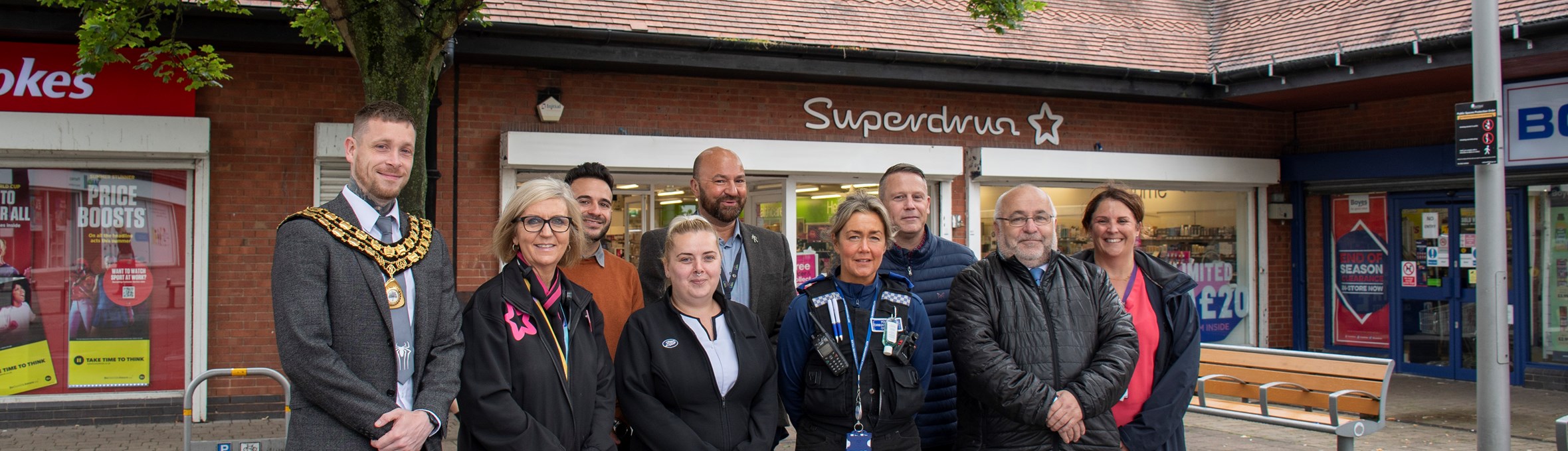 Councillors, officers and shop staff stand outside Superdrug in Kirkby, smiling at the camera 