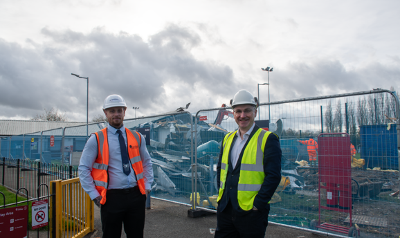 Two men in high vis stand in front of a half demolished changing room on Kingsway Park