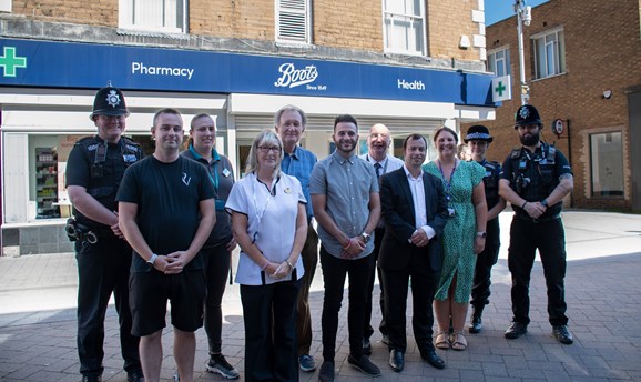 a group of people are stood on Hucknall High Street in front of the shop Boots 