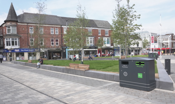 Portland square with grey paving, grass and trees  
