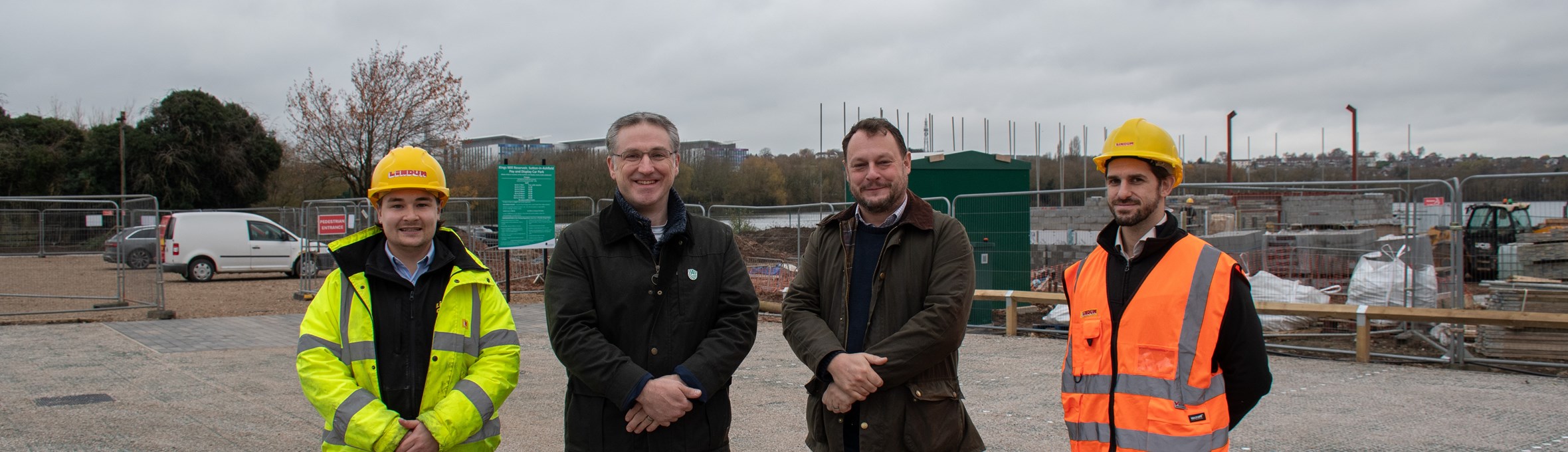 Four men smile at the camera, they are stood on the new car park 