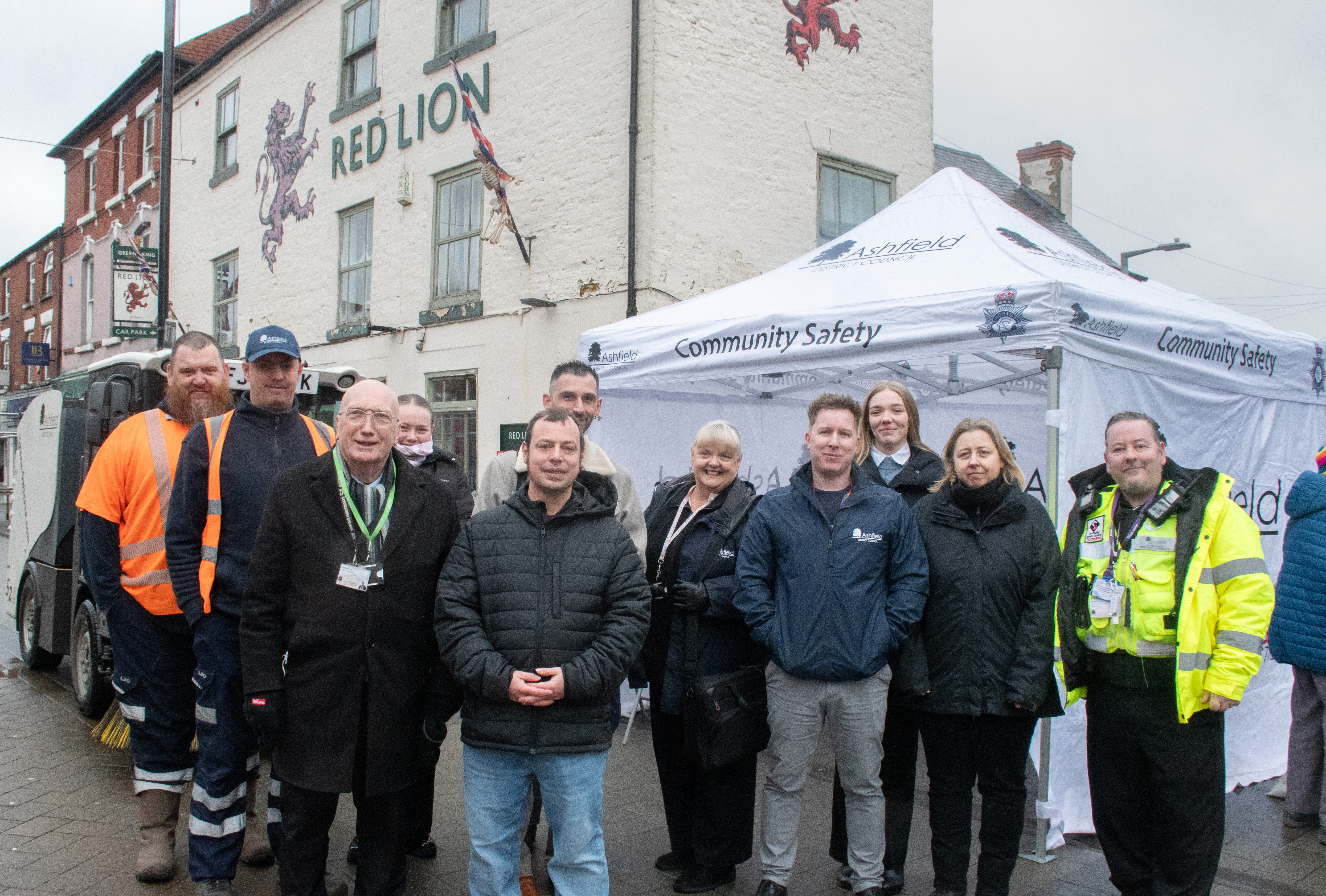 a group of people smile at the camera, some are in high-vis wear, all in front of a white tent 