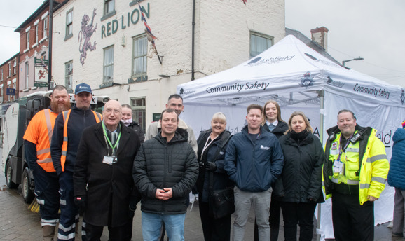 a group of people smile at the camera, some are in high-vis wear, all in front of a white tent 