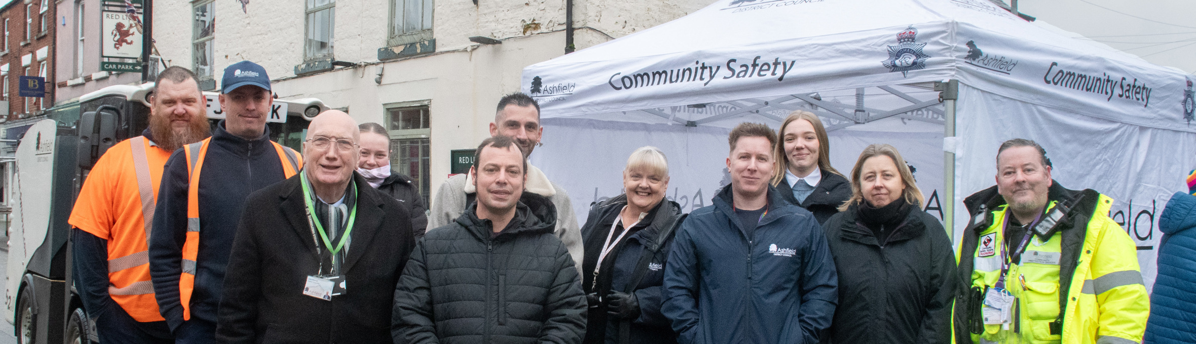 a group of people smile at the camera, some are in high-vis wear, all in front of a white tent 
