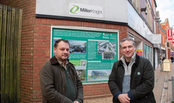 Two men stand in front of an empty shop in Sutton, they are smiling at the camera