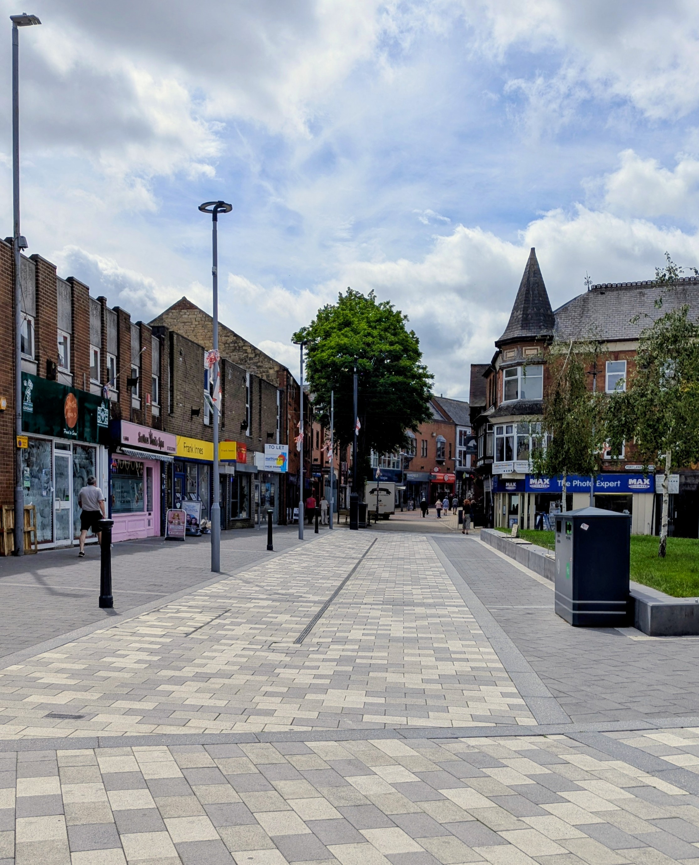 a pedestrianised shopping street with shop fronts of various colours 