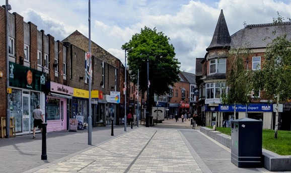 a pedestrianised shopping street with shop fronts of various colours 