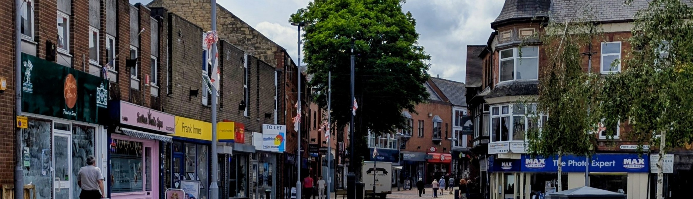a pedestrianised shopping street with shop fronts of various colours 