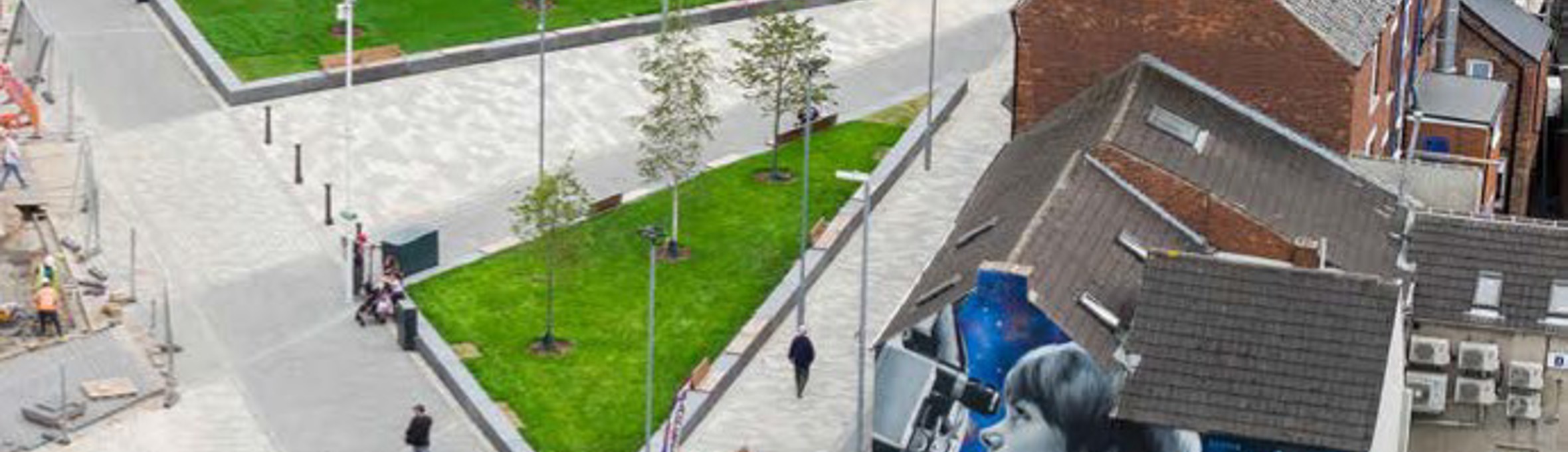 Image of houses and shops with seating in the middle and grass areas each side of the seating